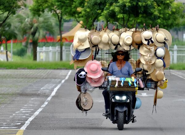 Người bán hàng rong với xe máy chở mũ trong vườn thú Đài Loan - Sputnik Việt Nam
