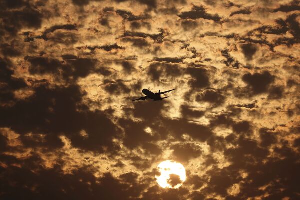 Hình bóng máy bay trên nền những đám mây phát sáng dưới ánh mặt trời lặn ở Ahmadabad, Ấn Độ - Sputnik Việt Nam