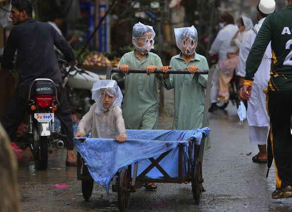 Các thiếu niên đội túi trên đầu trong trận mưa ở Peshawar, Pakistan - Sputnik Việt Nam