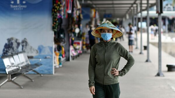 Một người phụ nữ đeo mặt nạ đi dọc bến cảng Tuần Châu ở Vịnh Hạ Long thuộc tỉnh phía đông bắc Quảng Ninh, Việt Nam. - Sputnik Việt Nam