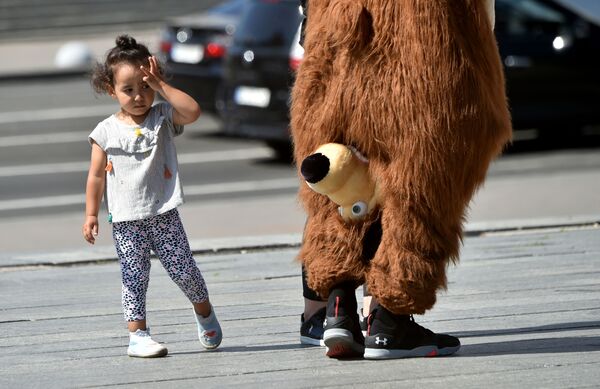Bé gái nhìn nghệ sĩ đường phố hóa trang thành một chú gấu trong bộ phim hoạt hình Masha và chú gấu ở Kiev, Ukraina - Sputnik Việt Nam