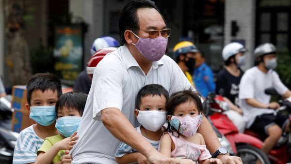Người đàn ông có con đi xe đạp, đeo mặt nạ bảo vệ, trên đường phố Hà Nội, Việt Nam - Sputnik Việt Nam