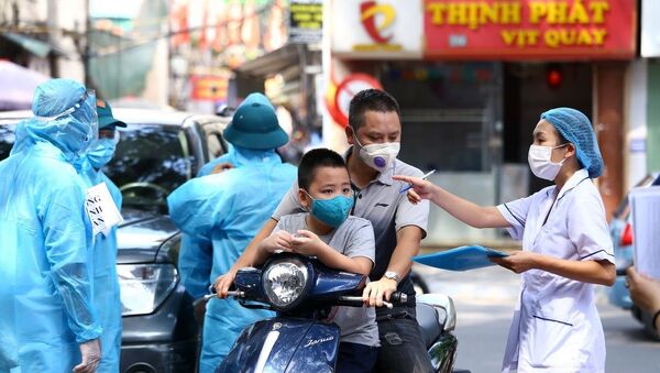Nhân viên y tế hướng dẫn người dân xếp hàng theo phường đã đăng ký. - Sputnik Việt Nam