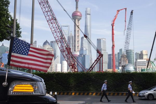 FILE - In this file photo taken Tuesday, July 30, 2019, Chinese traffic police officers walk by a U.S. flag on an embassy car outside a hotel in Shanghai where officials from both sides met for talks aimed at ending a tariff war. Both countries already have suffered heavy losses in a tariff war that erupted in 2018 over Beijing's technology ambitions and trade surplus. If talks on ending the dispute fail, the world could face downward pressure on trade at a time when the global economy is already reeling from the coronavirus pandemic. 
 - Sputnik Việt Nam