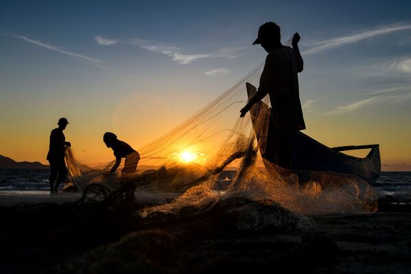 Ngư dân thu dọn lưới sau khi đánh cá vào lúc hoàng hôn ở Banda Aceh, Sumatra, Indonesia - Sputnik Việt Nam