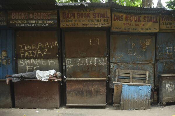 Người đàn ông ngủ trước quầy sách đóng cửa vào thời gian cách ly ban ngày được áp đặt chống lại sự gia tăng đột biến ca bệnh nhiễm Covid-19 ở Kolkata - Sputnik Việt Nam