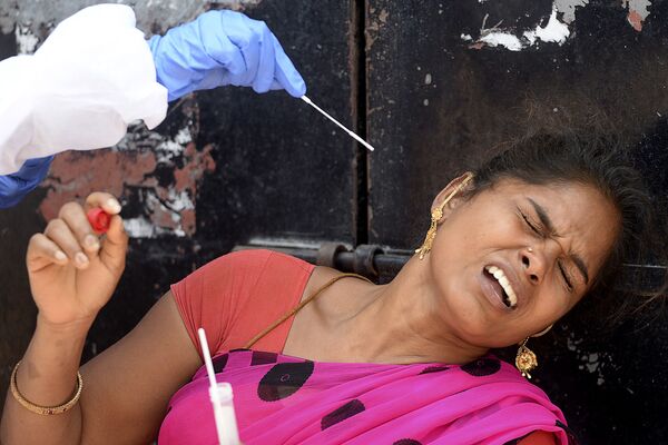 Nhân viên y tế lấy y phẩm của người phụ nữ để xét nghiệm Covid-19 trong một khu dân cư ở Chennai, Ấn Độ - Sputnik Việt Nam