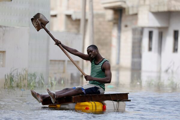 Người dân trên chiếc bè tự chế với chiếc xẻng lênh đênh qua những con phố ngập lụt sau trận mưa lớn ở Keur Massar, Senegal - Sputnik Việt Nam