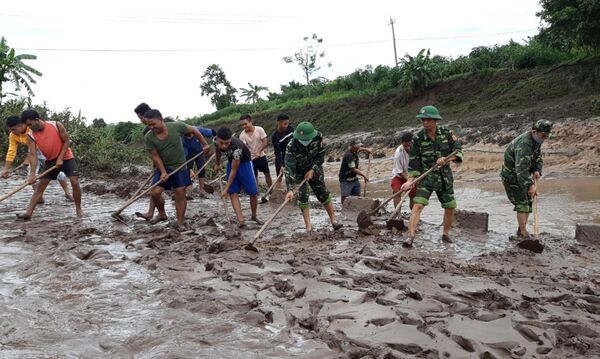 Người dân các xã miền núi Hướng Hóa thu dọn bùn đất bồi lấp trên các tuyến giao thông do bão số 5 gây ra.  - Sputnik Việt Nam