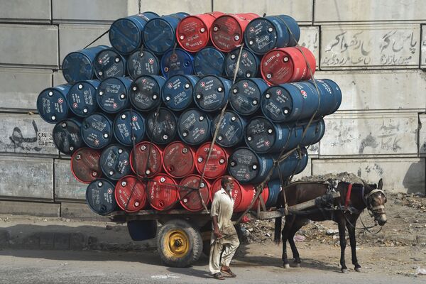 Người đàn ông bên cạnh xe chở đầy các thùng dầu trên đường phố ở Lahore, Pakistan - Sputnik Việt Nam