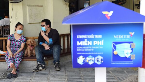Những người ngồi trong quán cà phê cạnh máy bán khẩu trang miễn phí ở Hà Nội. - Sputnik Việt Nam