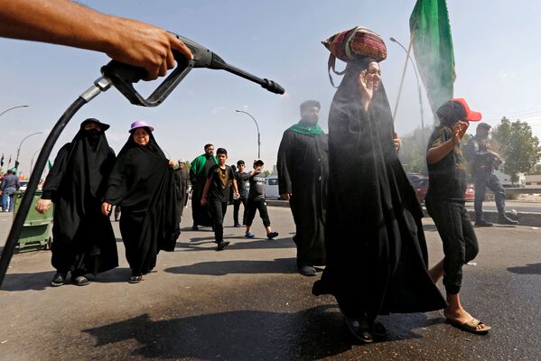 Nước bắn vào những người hành hương dòng Shia theo đạo Hồi ở Iraq trên đường đến thánh địa Kerbala trước nghi lễ thánh Arbaeen của người Shia ở Baghdad, Iraq - Sputnik Việt Nam