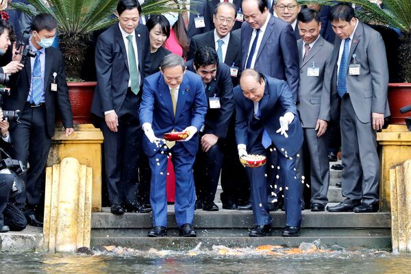 Thủ tướng Nhật Bản Yoshihide Suga và Thủ tướng Việt Nam Nguyễn Xuân Phúc cho cá ăn trong cuộc gặp tại Phủ Chủ tịch, Hà Nội - Sputnik Việt Nam