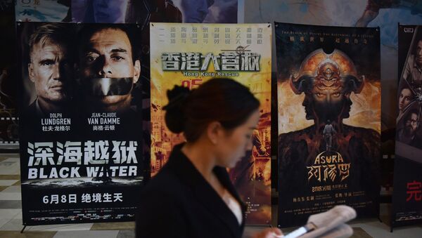 Một người phụ nữ nhìn vào điện thoại di động của mình gần áp phích phim bên ngoài rạp chiếu phim ở Bắc Kinh - Sputnik Việt Nam