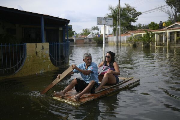 Người dân và chiếc bè làm bằng cánh cửa trên đường phố ngập lụt ở Maracay, Venezuela - Sputnik Việt Nam
