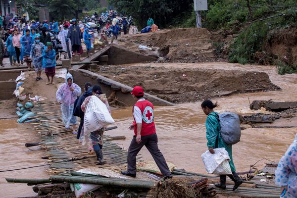 Người dân địa phương chở hàng cứu trợ của Hội Chữ thập đỏ qua cây cầu bị sập sau trận lở đất ở tỉnh Quảng Trị, Việt Nam - Sputnik Việt Nam