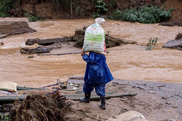Người dân địa phương chở hàng cứu trợ nhân đạo của Hội Chữ thập đỏ qua cây cầu bị sập sau trận lở đất ở tỉnh Quảng Trị, Việt Nam - Sputnik Việt Nam