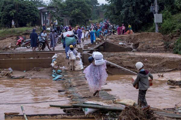 Người dân địa phương chở hàng cứu trợ của Hội Chữ thập đỏ qua cây cầu bị sập sau trận lở đất ở tỉnh Quảng Trị, Việt Nam - Sputnik Việt Nam