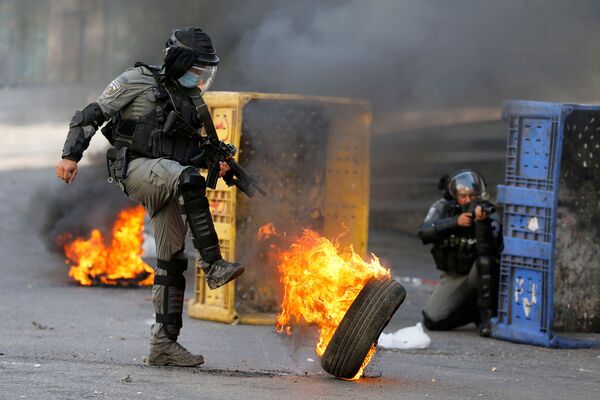 Sĩ quan cảnh sát Israel đá vào lốp xe đang cháy trong cuộc biểu tình chống Israel ở Hebron, Bờ Tây - Sputnik Việt Nam
