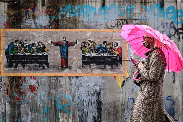 Người phụ nữ mang khẩu trang với hoạ tiết da báo trên nền graffiti của nghệ sĩ người Ý TvBoy ở Milan, Ý - Sputnik Việt Nam