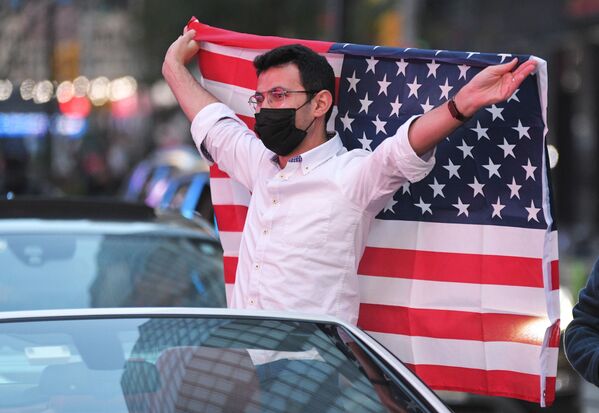Người đàn ông với lá cờ Mỹ tại Quảng trường Thời đại ở New York sau tin ứng cử viên đảng Dân chủ Joseph Biden giành chiến thắng trong cuộc bầu cử tổng thống Mỹ - Sputnik Việt Nam