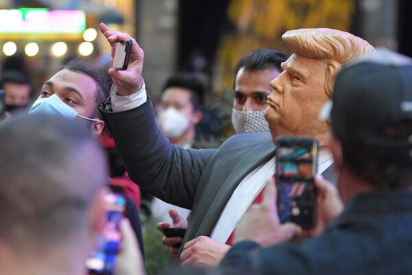 Dân chúng trên Quảng trường Thời đại ở New York chụp ảnh người đàn ông đeo mặt nạ Donald Trump - Sputnik Việt Nam
