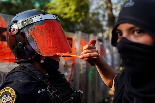 Cô gái bôi màu lên mũ bảo hiểm của nhân viên cảnh sát trong cuộc biểu tình chống bạo lực và sự bạo hành của cảnh sát ở Mexico City - Sputnik Việt Nam