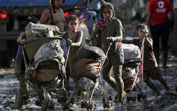 Trẻ em mang xe đẩy với đồ đạc ở một ngôi làng bị bão Vamco ở Philippines - Sputnik Việt Nam