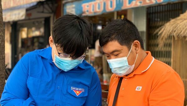 Đoàn viên thanh niên tình nguyện hướng dẫn người dân cài đặt ứng dụng Bluezone trên điện thoại. - Sputnik Việt Nam