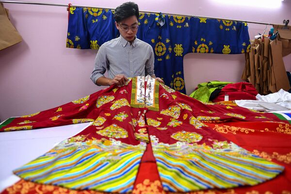 Doanh nhân Nguyễn Đức Lộc kiểm tra các mẫu cổ phục trên cơ sở mô-tip truyền thống ở Hà Nội  - Sputnik Việt Nam