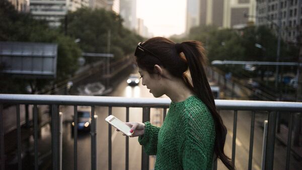 Một người phụ nữ sử dụng điện thoại khi đi qua cầu ở Bắc Kinh - Sputnik Việt Nam