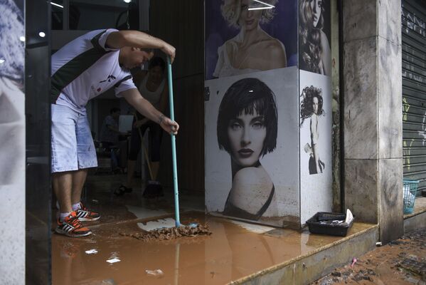 Người đàn ông thu dọn bùn bẩn trong cửa hàng sau trận lụt ở Belo Horizonte, Brazil - Sputnik Việt Nam