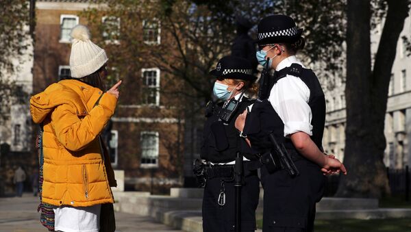 Cảnh sát đeo khẩu trang và những người phản đối lệnh hạn chế ở London, Anh. - Sputnik Việt Nam