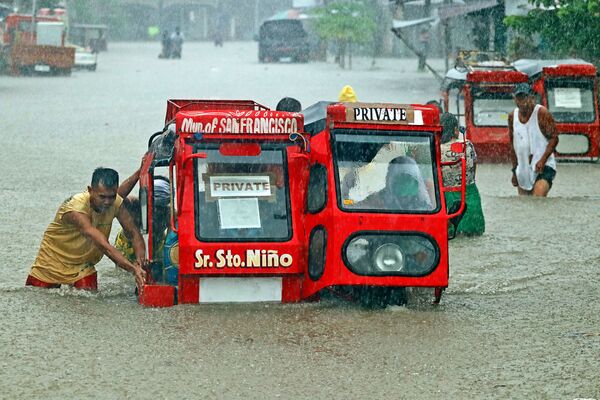 Mọi người đẩy xe ba bánh trên con phố ngập lụt ở San Francisco, Philippines - Sputnik Việt Nam