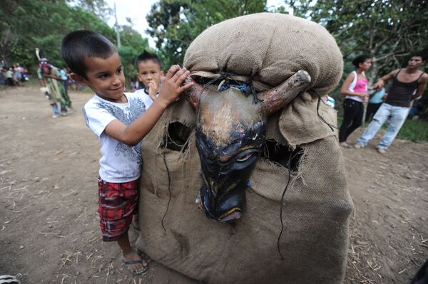 Cậu bé chơi với  người tham gia lễ hội Feast of the Devil trong trang phục bò tót ở Costa Rica - Sputnik Việt Nam