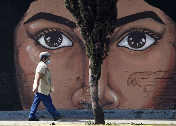 Một phụ nữ đi ngang qua bức vẽ graffiti trên bức tường nghĩa trang San Nicolas Tolentino ở  Istapalapa, Mexico - Sputnik Việt Nam