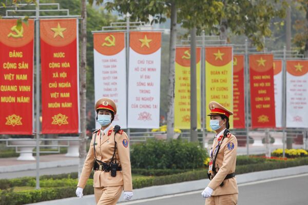 Nữ nhân viên cảnh sát ngang qua biển hiệu tại Trung tâm Hội nghị Quốc gia, nơi diễn ra Đại hội lần thứ XIII của Đảng Cộng sản Việt Nam  - Sputnik Việt Nam