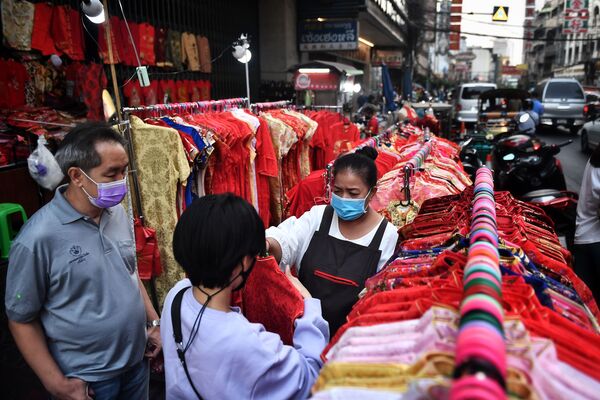 Người bán hàng giúp khách mua sắm chọn quần áo trước Tết Nguyên đán ở khu phố người Hoa, Bangkok, Thái Lan - Sputnik Việt Nam