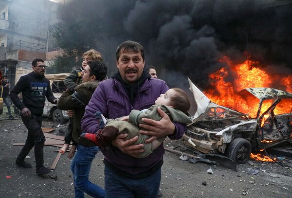 Người đàn ông bế em bé bị thương trong vụ nổ ô tô ở thành phố Azaz của Syria - Sputnik Việt Nam