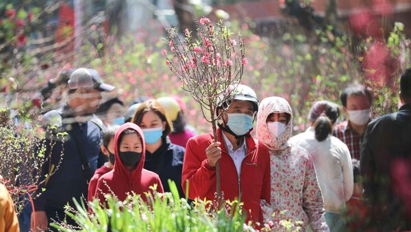 Người dân đi chợ hoa Tết truyền thống trong ngày 29 Tết đều thực hiện nghiêm túc việc đeo khẩu trang để phòng chống dịch. - Sputnik Việt Nam