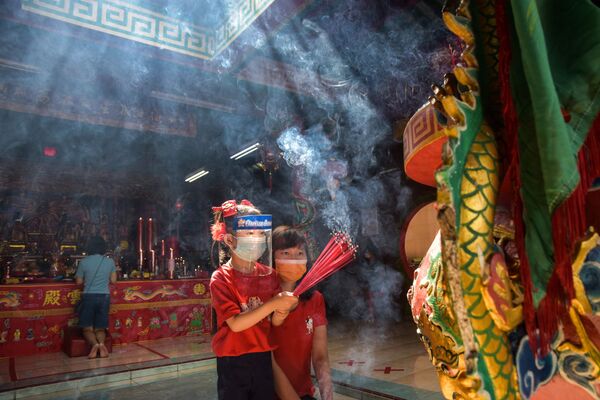 Bé gái mang tấm chắn giọt bắn cùng mẹ dâng hương trong dịp Năm mới tại ngôi đền ở Indonesia - Sputnik Việt Nam