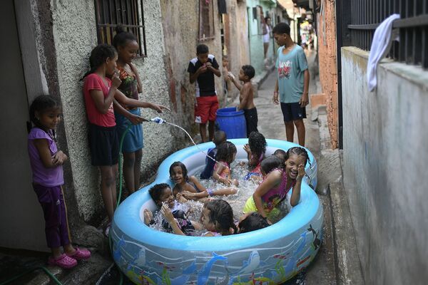 Bọn trẻ chơi đùa trong chiếc hồ bơm hơi trên một đường phố của Caracas, Venezuela - Sputnik Việt Nam
