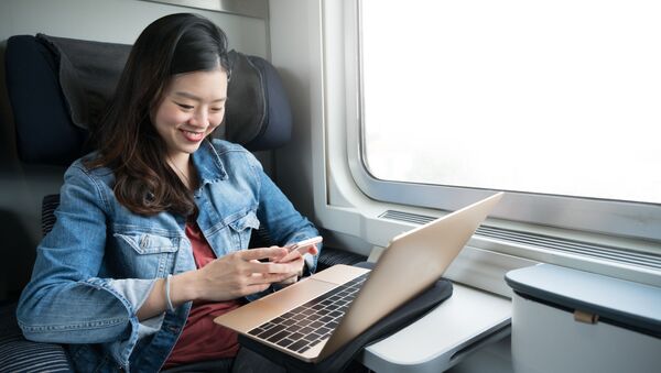 Cô gái đi trên tàu với máy tính xách tay và điện thoại - Sputnik Việt Nam