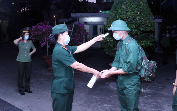 Các thanh niên lên đường nhập ngũ được kiểm tra thân nhiệt, rửa tay sát khuẩn tại điểm giao nhận quân tổ chức tại Quận 5, Thành phố Hồ Chí Minh. - Sputnik Việt Nam