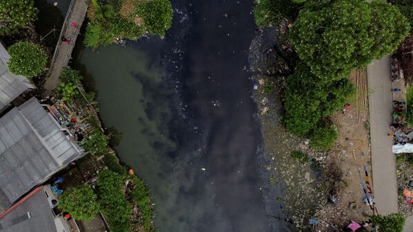 Người dân câu cá từ cây cầu gỗ trên sông Pisang Batu, chảy qua khu vực đông dân cư và nhiễm rác thải sinh hoạt, ở Bekasi, ngoại ô Jakarta, Indonesia - Sputnik Việt Nam