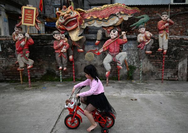Cô gái đạp xe lướt qua tác phẩm sắp đặt mang tên Múa sư tử của nghệ sĩ Nguyễn Xuân Lâm tại không gian nghệ thuật Phúc Tân, Hà Nội - Sputnik Việt Nam