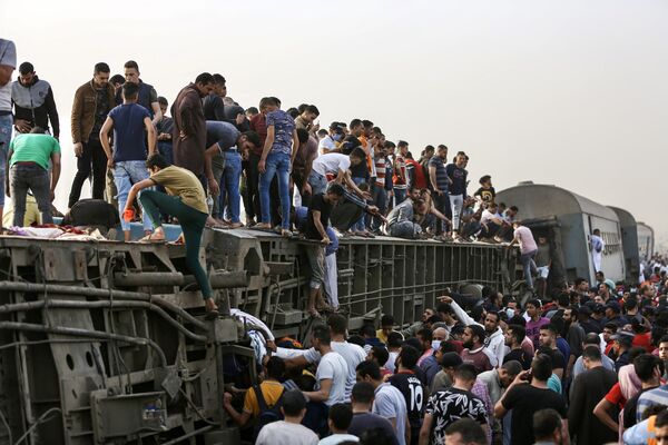 Mọi người leo lên toa tàu bị lật sau vụ tai nạn tàu hỏa ở thành phố Tuh, Ai Cập - Sputnik Việt Nam