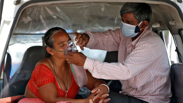 Người chồng điều chỉnh mặt nạ dưỡng khí cho vợ trong khi hai người đang ngồi trong xe chờ được nhập viện, Ấn Độ - Sputnik Việt Nam