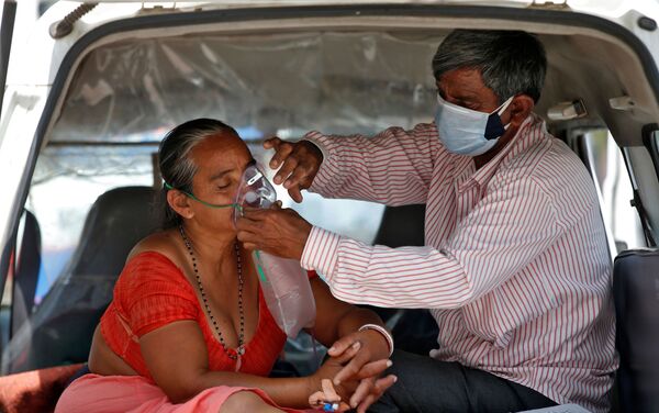 Người chồng điều chỉnh mặt nạ dưỡng khí cho vợ trong khi hai người đang ngồi trong xe chờ được nhập viện, Ấn Độ - Sputnik Việt Nam