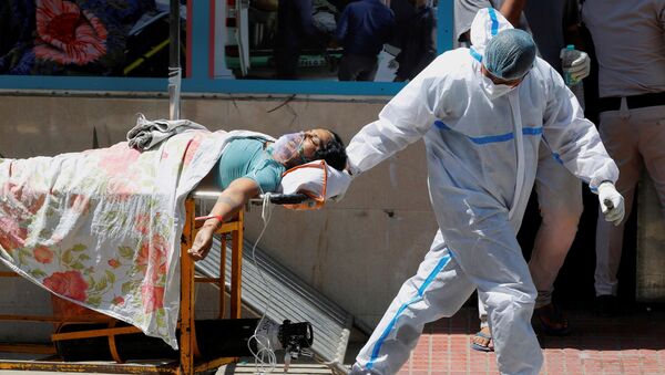 FILE PHOTO: Một nhân viên y tế mang thiết bị bảo vệ cá nhân (PPE) bế một bệnh nhân mắc bệnh do coronavirus (COVID-19) bên ngoài khu cấp cứu tại bệnh viện Guru Teg Bahadur, ở New Delhi, Ấn Độ, ngày 24 tháng 4 năm 2021. - Sputnik Việt Nam